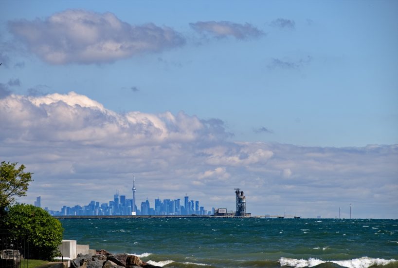 Stunning Toronto cityscape with waterfront and clouds, showcasing urban skyline and CN Tower in view.